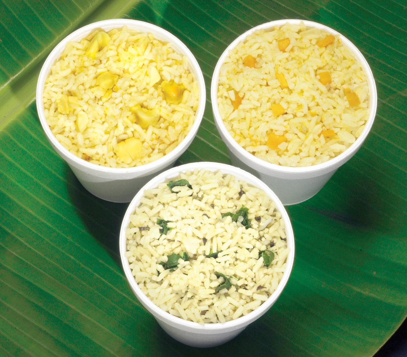 Cups of callaloo rice, pumpkin rice and rice and peas